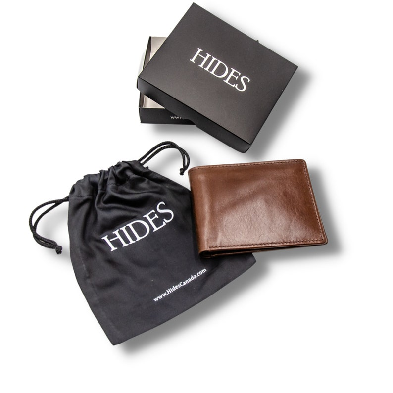 May include: A brown leather wallet with the word "HIDES" embossed on it. The wallet is in a black drawstring bag with the same logo. The wallet is also in a black box with the word "HIDES" on it.