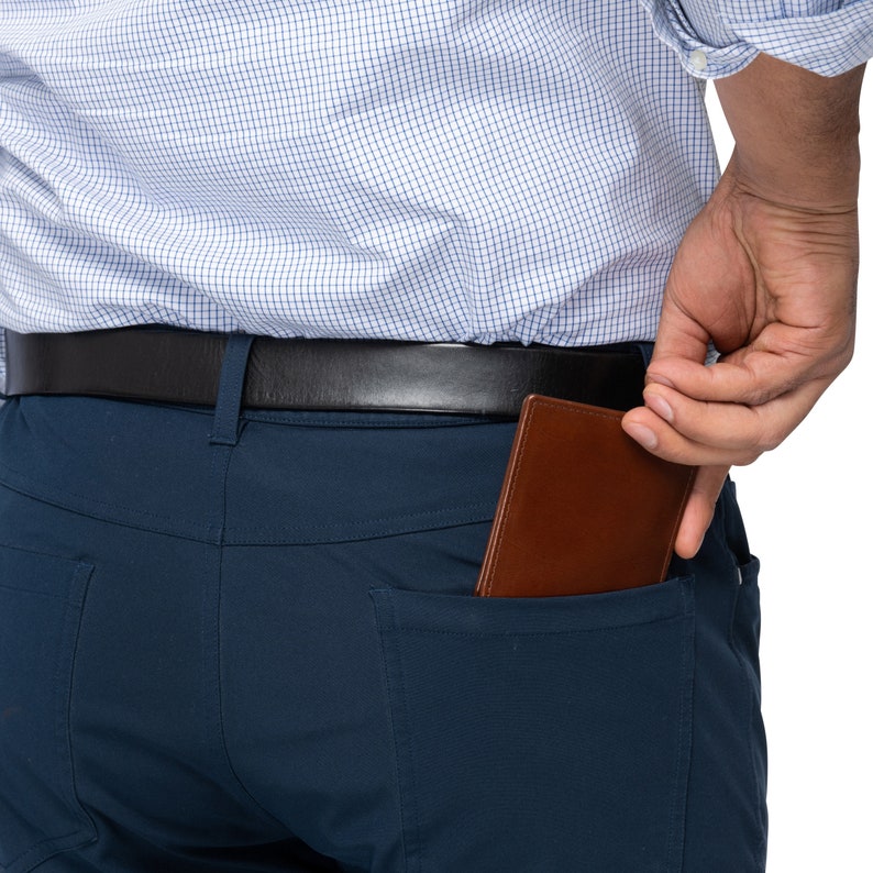 May include: A person wearing a blue button-down shirt and dark blue pants with a brown leather wallet in the back pocket.