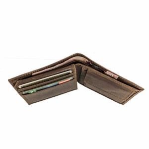 Pu&ograve; includere: Un portafoglio in pelle marrone con pi&ugrave; slot per carte e un portafoglio per banconote. Il portafoglio &egrave; aperto e contiene diverse carte e banconote.