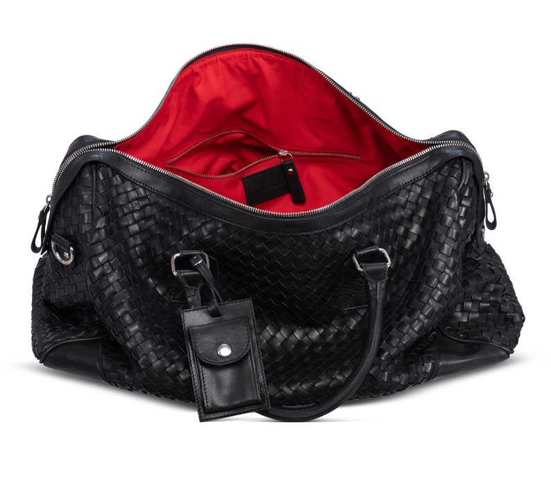 May include: Black leather woven travel bag with a red interior lining and a small leather tag attached to the handle.