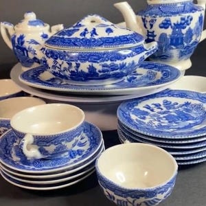 May include: A collection of blue and white Willow pattern china. The set includes a teapot, sugar bowl, serving dish, cups, saucers, and bowls. The china features a detailed landscape design.