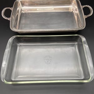May include: A rectangular silver-toned metal serving tray with rope-style edges and two side handles, paired with a clear rectangular Pyrex glass baking dish featuring the text PYREX MADE IN U.S.A. stamped in the center of the base.
