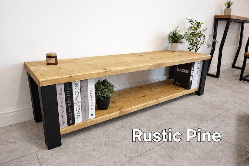 May include: A rustic pine bench with a natural wood top and a lower shelf. The legs are black. The bench holds books, a small potted plant, and a jar. The text "Rustic Pine" is at the bottom of the image.