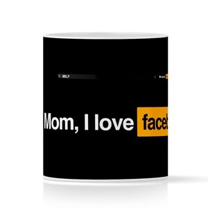 Puede incluir: Una taza de cerámica blanca con fondo negro y el texto "Mom, I love facebook" en letras blancas. La palabra "facebook" está en un rectángulo amarillo.