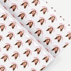 Op de afbeelding: Wit inpakpapier met een herhalend patroon van een vrouwengezicht en de tekst "JASMINE IS 27!" in roze.
