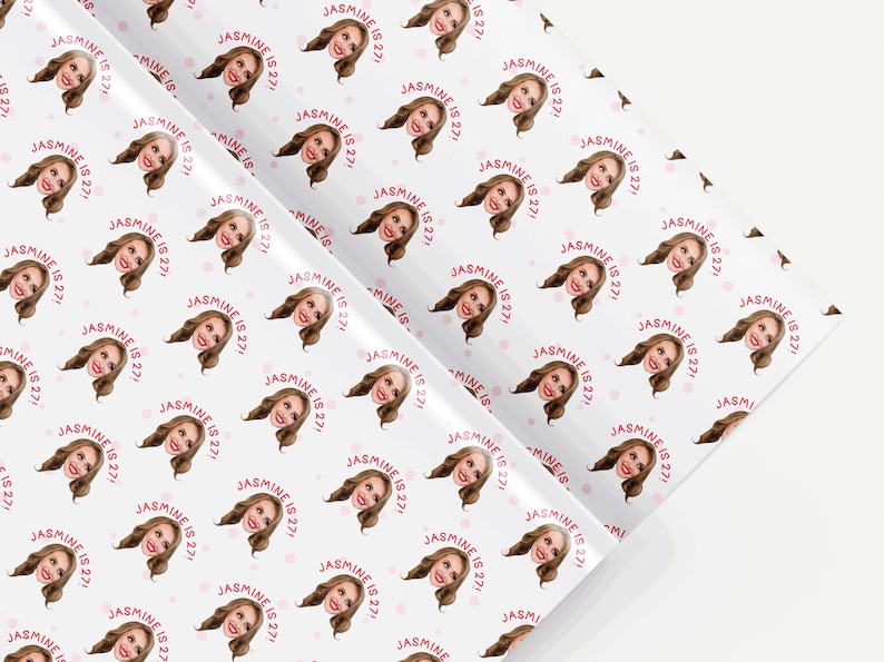 Op de afbeelding: Wit inpakpapier met een herhalend patroon van een vrouwengezicht en de tekst "JASMINE IS 27!" in roze.