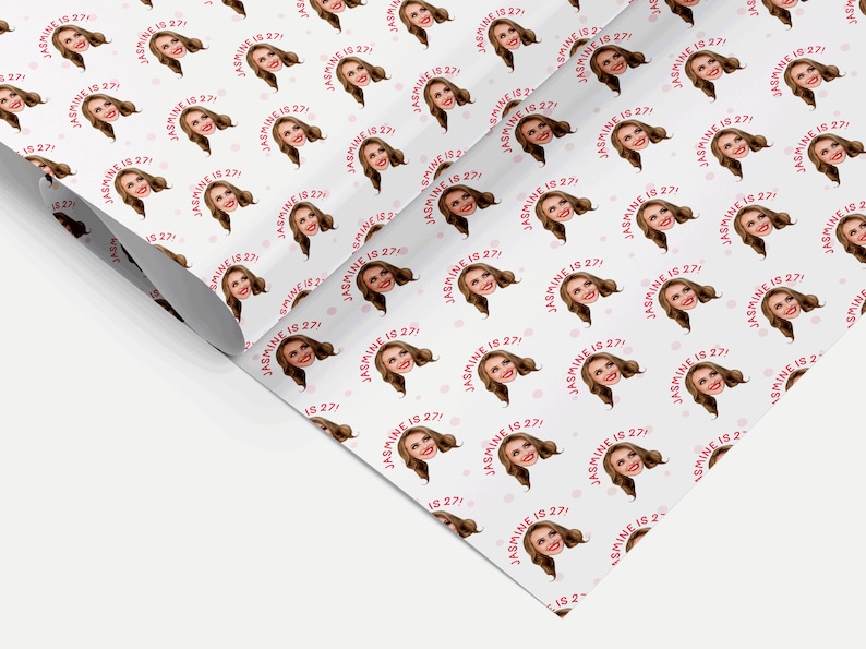 Op de afbeelding: Wit inpakpapier met een herhalend patroon van een vrouwen gezicht met de tekst "JASMINE IS 27!" in roze. De achtergrond heeft kleine roze stippen.