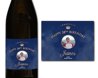May include: A blue and gold champagne bottle label with a crown and the text "Champagne Happy 28th Birthday James Love, Mom & Dad". A photo of a person is in a circle on the label.