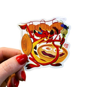 May include: A red dragon with a yellow and orange face holding a gong and a stick with a blue bird on top. The dragon is surrounded by red lanterns. The text "jillian xaye art" is in the bottom right corner.