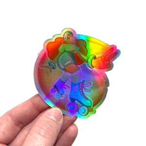 Puede incluir: Una pegatina holográfica con una mujer que lleva patines y sopla una burbuja. La pegatina tiene un acabado iridiscente arcoíris y un fondo punteado.