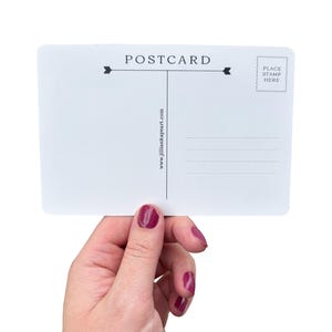 May include: A white postcard with the word "POSTCARD" printed at the top, with lines for writing and a stamp area. The website address "www.jilliankayeart.com" is printed vertically. The postcard is held by a hand with painted nails.