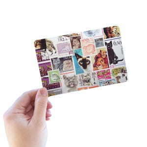 K&ouml;nnte beinhalten: Eine rechteckige Karte mit einer Collage aus verschiedenen Briefmarken, die jeweils unterschiedliche Katzenillustrationen zeigen, darunter Hausrassen und Zeichentrickfiguren, mit sichtbarem Text wie USA 22, 6.50 und internationalen Markierungen.