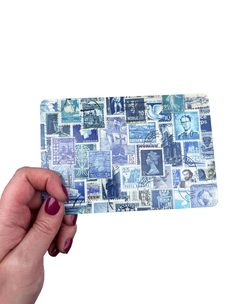 May include: A rectangular card featuring a collage of blue and white vintage postage stamps. The stamps depict portraits, buildings, and ships. The card is held in a hand with dark red nail polish. The stamps are from various countries.