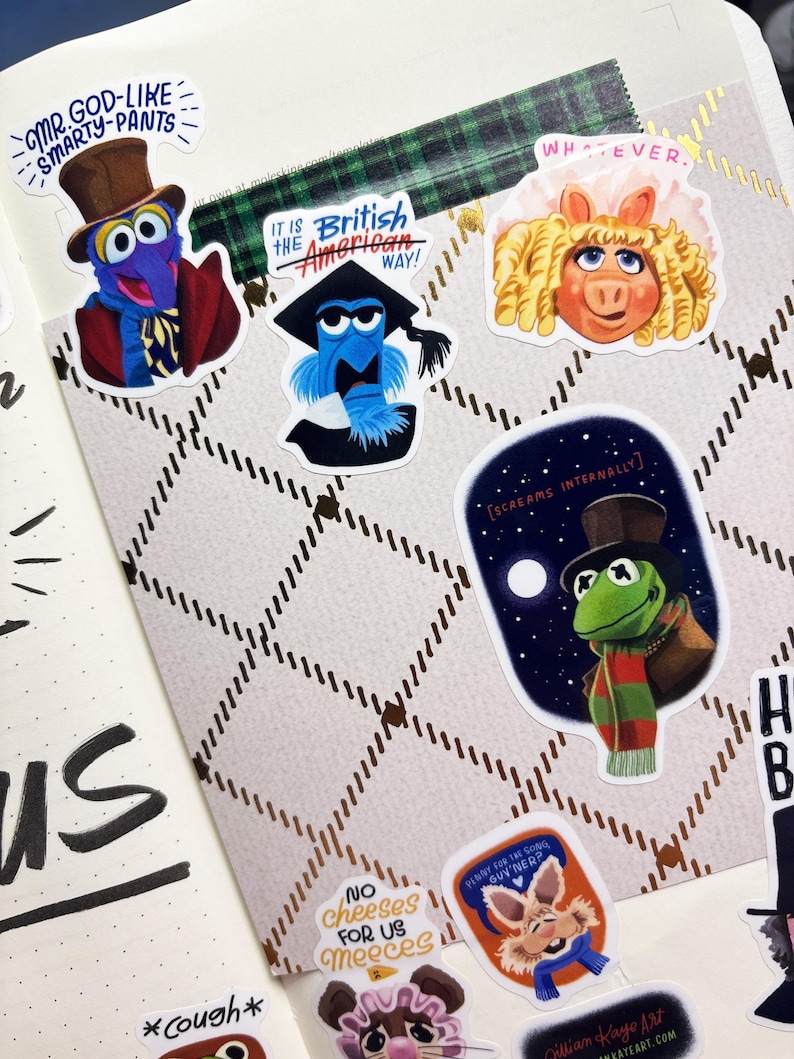 Op de afbeelding: Een verzameling kleurrijke stickers met Muppet-personages. De stickers bevatten Gonzo, Miss Piggy en Kermit, met teksten als "Mr. God-like Smarty-Pants" en "It is the British American Way!". De stickers bevinden zich op een patroonachtergrond.