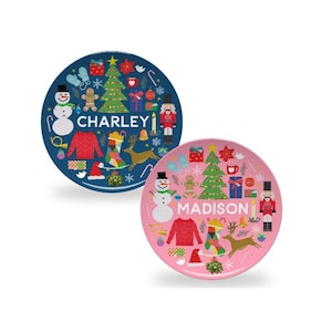 May include: Two personalized Christmas plates, one blue with the name "CHARLEY" and one pink with the name "MADISON". Both plates feature a Christmas tree, snowman, reindeer, and other festive icons.