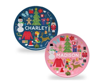 May include: Two personalized Christmas plates, one blue with the name "CHARLEY" and one pink with the name "MADISON". Both plates feature a Christmas tree, snowman, reindeer, and other festive icons.