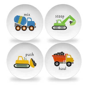 May include: Four white plates with colorful construction vehicles and words describing their actions: mix, scoop, push, haul.