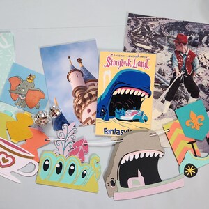 May include: A collection of colorful paper cutouts and postcards featuring whimsical designs. Includes a Dumbo the elephant illustration, a Storybook Land book cover, and a vintage photo. Decorative elements include a teacup, a carousel horse, and a circus tent.