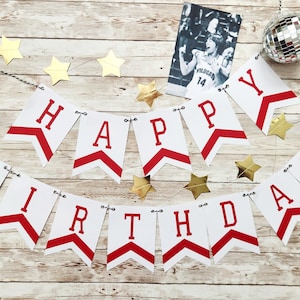 May include: A white banner with red lettering that spells out "HAPPY BIRTHDAY" is strung across the image. Gold star-shaped decorations and a small disco ball are also present. A black and white photo is also included.