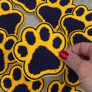 May include: Multiple yellow and navy blue paw print patches. The paw prints are fuzzy and have a black outline.