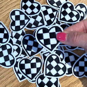 May include: A collection of black and white checkered heart-shaped patches. The patches are made of fabric and have a white outline.