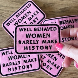 May include: Pink fabric patches with black embroidered text that reads "Well Behaved Women Rarely Make History".