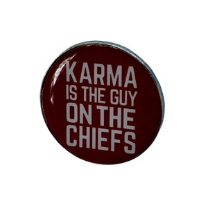 Puede incluir: Un pin redondo rojo con borde plateado. El pin dice "Karma is the guy on the Chiefs" en texto blanco.