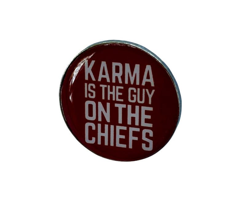 Puede incluir: Un pin redondo rojo con borde plateado. El pin dice "Karma is the guy on the Chiefs" en texto blanco.