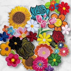 May include: A collection of colorful, embroidered flower patches in various shapes and sizes. The patches include a sunflower, roses, daisies, and other floral designs in shades of yellow, blue, red, pink, and green. Each patch has a white border.