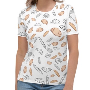 Puede incluir: Camiseta blanca con un patrón de diferentes tipos de pan, incluyendo baguettes, croissants y bollos.