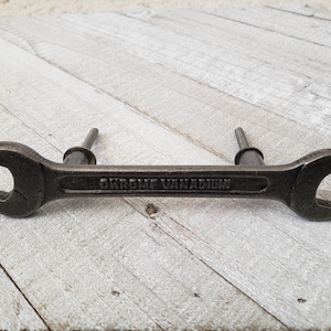 May include: A black metal wrench-shaped cabinet pull with the words "Chrome Vanadium" engraved on the handle.