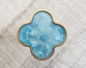 Tiradores de cajón con forma de trébol azul claro y tiradores de cómoda con detalles dorados.