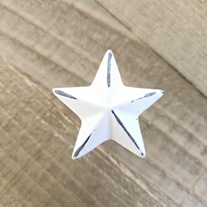 May include: White painted metal star with a distressed finish. The star is five-pointed and has a slightly raised centre.