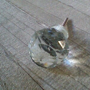 May include: A clear glass crystal cabinet knob with a silver metal screw.