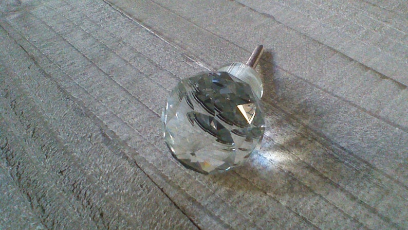 May include: A clear glass crystal cabinet knob with a silver metal screw.