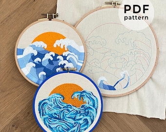 May include: Three embroidery hoops with ocean wave designs. Two hoops feature completed embroidery with blue waves and an orange sun. The third hoop shows a wave pattern outline. The text "PDF pattern" is visible.