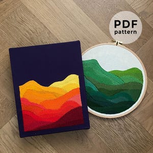 May include: Two embroidery patterns of colourful mountain ranges. The first pattern is a sunset-coloured mountain range on a dark blue background. The second pattern is a green mountain range on a white background. Both patterns are in embroidery hoops. The text "PDF pattern" is on a white circle with a black outline.