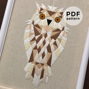 May include: Geometric owl embroidery pattern in shades of brown, white, and beige. The owl is stitched with a detailed, intricate design. The pattern is available as a PDF download. PDF pattern
