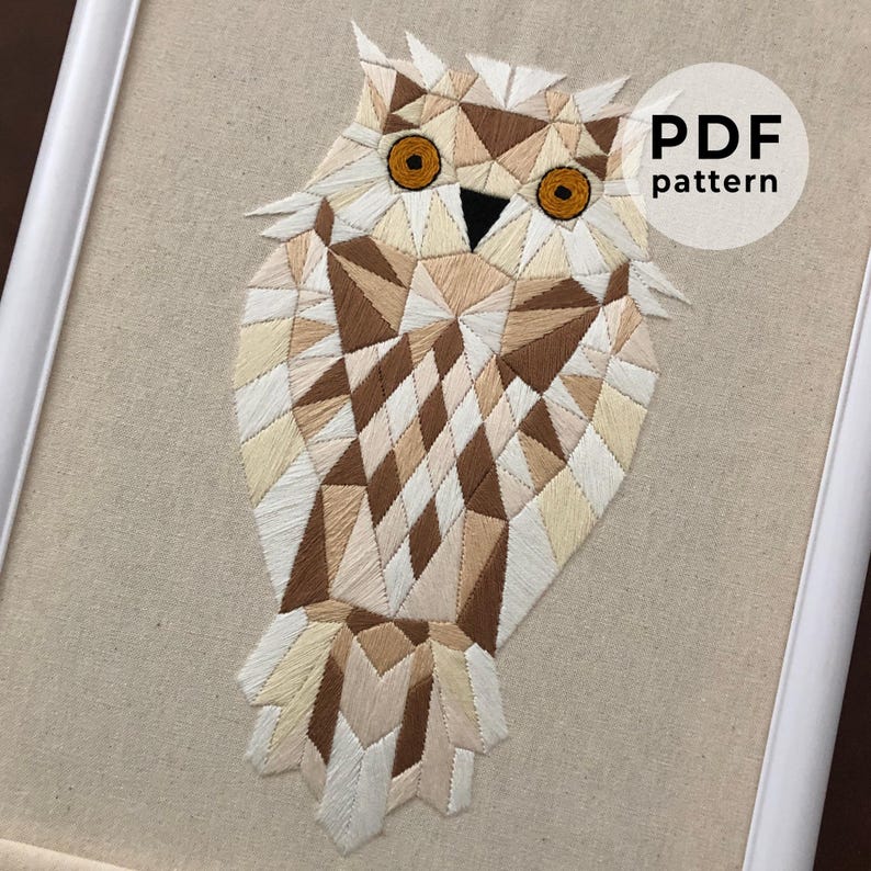 May include: Geometric owl embroidery pattern in shades of brown, white, and beige. The owl is stitched with a detailed, intricate design. The pattern is available as a PDF download. PDF pattern