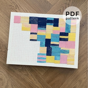 May include: A woven textile art piece with a grid pattern on a white canvas. The artwork features a patchwork design in shades of pink, yellow, blue, and navy. The text "PDF pattern" is in a white circle in the upper right corner.