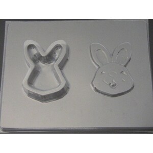 May include: A clear plastic mold for making chocolate bunnies. The mold has two cavities, one for a bunny head and one for a bunny body.