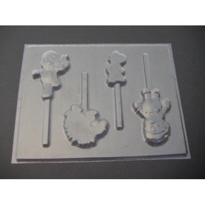 Może przedstawiać: Przezroczysta plastikowa forma do cukierków z czterema różnymi kształtami postaci: dziewczynką, misiem, kwiatkiem i bałwanem. Każdy kształt ma patyczek. Idealna do robienia lizaków lub czekoladek.