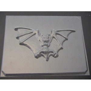 May include: A clear plastic mold for making a bat-shaped cake or other edible treat. The mold features a detailed design of a bat with outstretched wings.