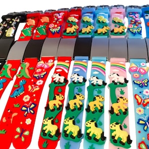 May include: A collection of colorful children's belts with various designs. Belts feature dinosaurs, butterflies, horses, rainbows, and sports balls. The belts have metal buckles and are in various colors including red, blue, and black.