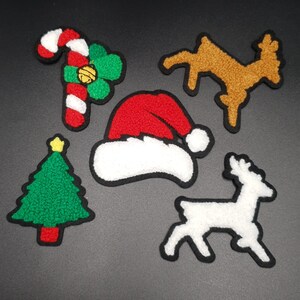 Peut inclure: Cinq décorations de Noël en feutre : une canne en sucre rouge et blanche, un trèfle vert et blanc, un bonnet de Père Noël rouge et blanc, un sapin de Noël vert et un renne blanc.