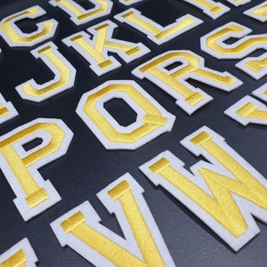 May include: Gold and white felt letters of the alphabet, including the letters C, J, K, L, P, Q, R, S, V, and W.