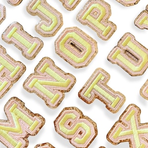 May include: A collection of felt letter patches in a variety of colors, including pink and yellow. The letters are embroidered with a white outline and have a glittery texture.