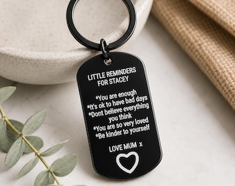 May include: A black metal dog tag keychain featuring white engraved text that reads: LITTLE REMINDERS FOR STACEY, followed by a list of affirmations including You are enough, It's ok to have bad days, Dont believe everything you think, You are so very loved, Be kinder to yourself, and LOVE MUM x with a heart icon.
