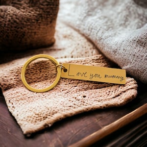 May include: Gold-toned keyring with a rectangular tag engraved with the handwritten message "Love you mummy".