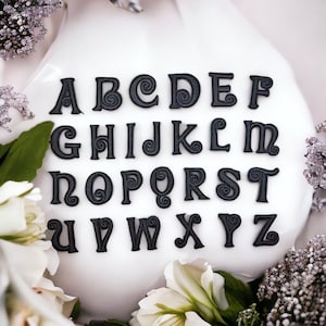 Peut inclure: Autocollants en lettres noires avec un design de spirale décoratif. Les lettres sont disposées en ordre alphabétique sur un fond blanc.